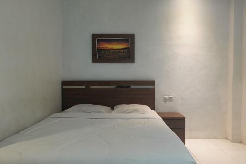 1 dormitorio con 1 cama y una foto en la pared en OYO 93929 Erbee Inn en Makassar