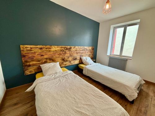 two beds in a room with a wall at Appartement 6 personnes - lit King size - balnéo - wifi in Le Puy-en-Velay