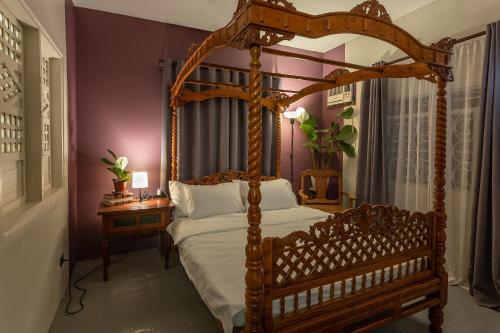 a bedroom with a wooden canopy bed and a table at Villa Raya w Outdoor Cinema, Bonfire, Treehouse & Parking in Vigan