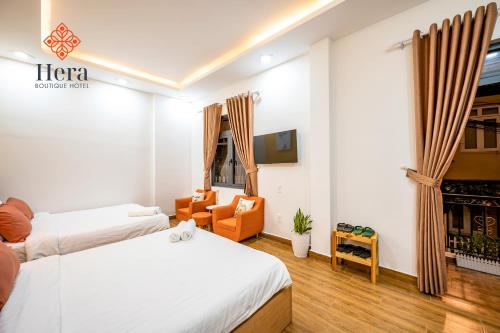 Hera Hotel Đà Lạt في دالات: غرفة فندقية بسريرين وكرسي