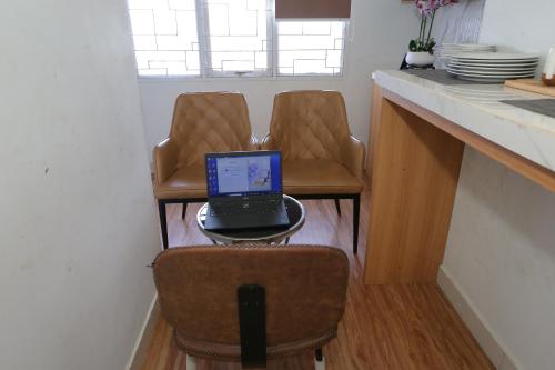 un computer portatile seduto su un tavolo con due sedie di OYO 93933 King's Room a Bekasi