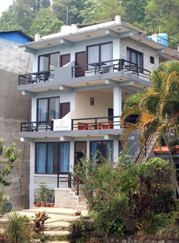 un edificio blanco con balcones y una palmera en The Orchards - 果园, en Pokhara