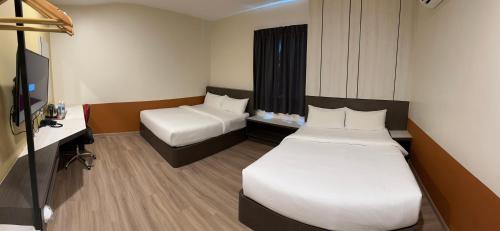 um quarto de hotel com duas camas e uma secretária em T SQUARE HOTEL (IPOH) em Ipoh