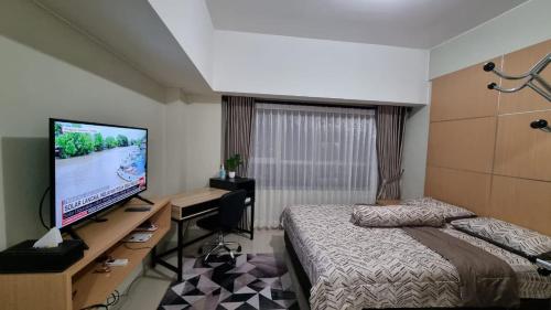 een slaapkamer met een bed en een flatscreen-tv bij Capital O 93935 Kukami Rooms in Bekasi