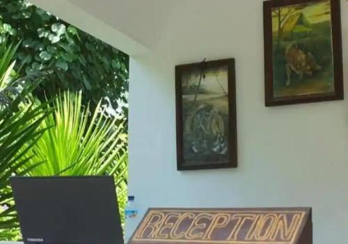 twee foto's aan een muur met een laptop op een bureau bij Capital O 93935 Kukami Rooms in Bekasi