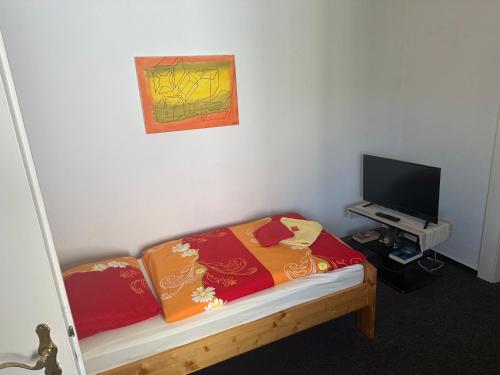 a small room with a bed and a flat screen tv at Die kleine Pension in Delmenhorst
