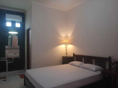 sypialnia z łóżkiem i lampką na ścianie w obiekcie Capital O 93938 Wisma Pamungkas Syariah w mieście Sleman