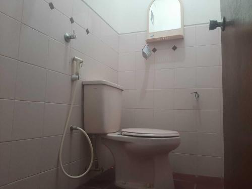 a bathroom with a white toilet and a window at Capital O 93938 Wisma Pamungkas Syariah in Sleman