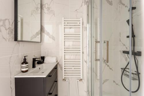 une salle de bain blanche avec un lavabo et une douche dans l'établissement Square Villaret Studio, à Paris