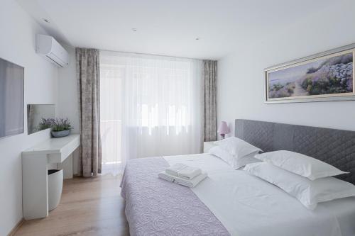 a white bedroom with a large bed with white pillows at Apartment Satureja Montana in Split