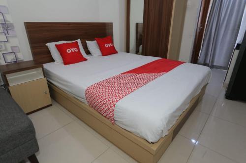 een slaapkamer met een bed met rode kussens erop bij OYO 93948 Bunda Rachma Rooms in Parungmalela