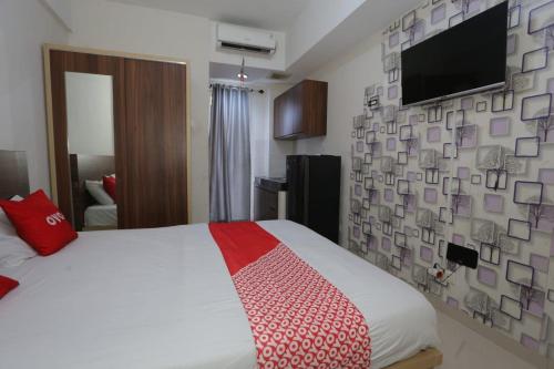 een slaapkamer met een bed en een tv aan de muur bij OYO 93948 Bunda Rachma Rooms in Parungmalela