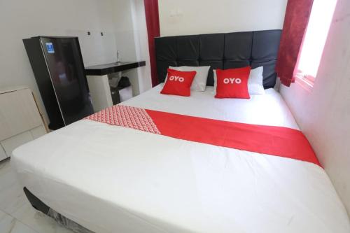 een groot wit bed met twee rode kussens erop bij OYO 93948 Bunda Rachma Rooms in Parungmalela