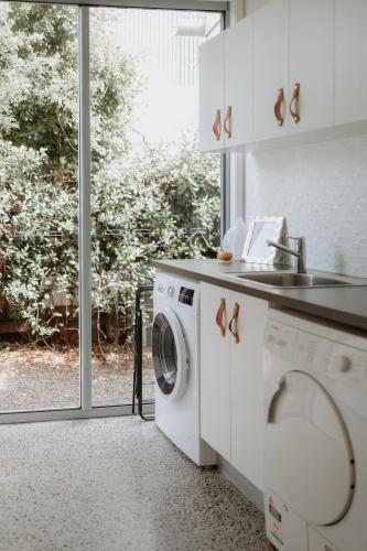 a kitchen with a washing machine and a sink at Gorgeous 5 bedroom beach house. Dog/Kid Friendly. in Marcoola