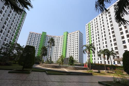 Deux grands bâtiments blancs avec des palmiers devant eux dans l'établissement Super OYO Capital O 93910 Asia Rooms at Green Lake View Ciputat, à Tangerang