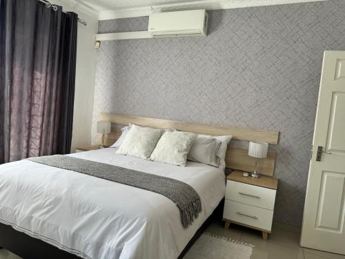 a bedroom with a large white bed and a wall at Hi-Life Villa in Gaborone