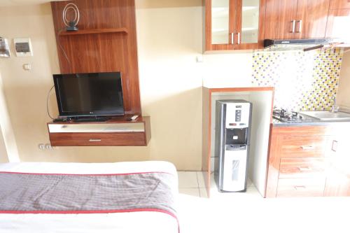 cocina pequeña con TV y nevera en Super OYO Capital O 93910 Asia Rooms at Green Lake View Ciputat en Tangerang