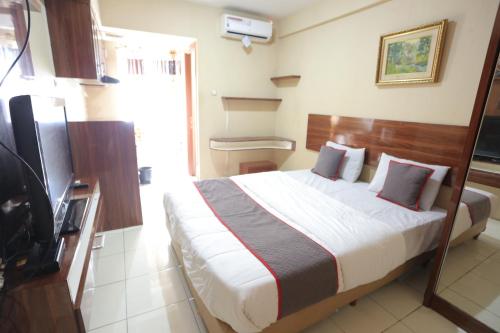 a hotel room with a bed and a television at Super OYO Capital O 93910 Asia Rooms at Green Lake View Ciputat in Tangerang