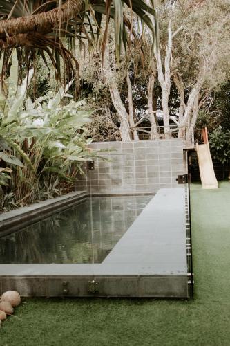 a swimming pool in a garden with grass and trees at Gorgeous 5 bedroom beach house. Dog/Kid Friendly. in Marcoola