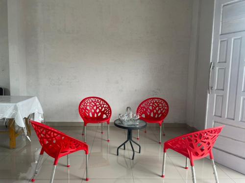 OYO 93947 Bahagia Guest House في ميدان: أربعة كراسي حمراء وطاولة في الغرفة