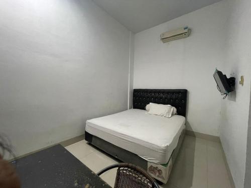 Habitación pequeña con cama y TV. en OYO 93947 Bahagia Guest House, en Medan