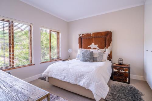 a bedroom with a large bed with a wooden headboard at Luxury , space and views - Pezula Villa 13 in Knysna