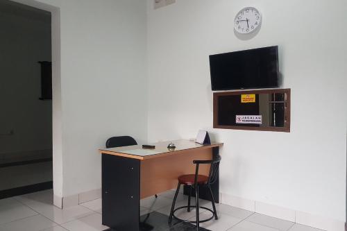 een bureau met 2 krukken en een tv aan de muur bij OYO 93951 Family Guesthouse in Medan