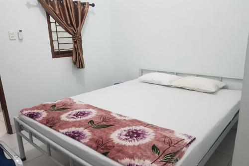 een wit bed met een bloemendeken erop bij OYO 93951 Family Guesthouse in Medan