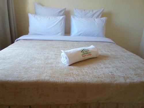 a hotel bed with a bag of towels on it at Kulu Lodge Apartments in Lusaka