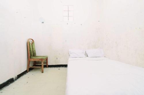 a bedroom with a bed and a chair in it at SPOT ON 93956 Siliwangi Guest House Syariah in Bandung