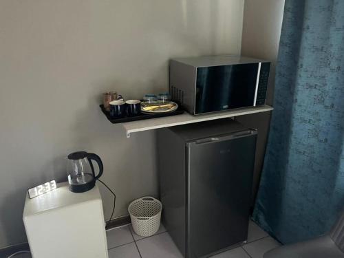 eine Mikrowelle auf einem Regal neben einem kleinen Kühlschrank in der Unterkunft Shiloh Shared in Gaborone