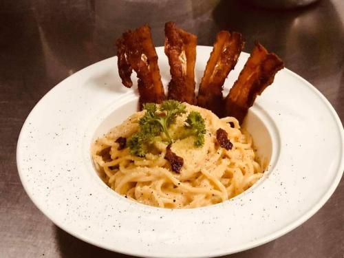 a white bowl of pasta with bacon and broccoli at @888byChefKong in Koh Tao