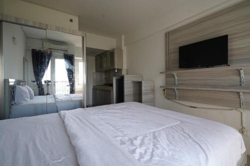 a bedroom with a white bed and a mirror at Capital O 93959 Apartement Gateway Cicadas By Mg Property in Bandung