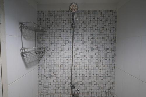 y baño con ducha y pared de azulejos. en Capital O 93959 Apartement Gateway Cicadas By Mg Property en Bandung