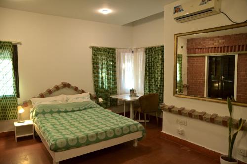 um quarto com uma cama, uma mesa e um espelho em Namma Ashram em Bangalore