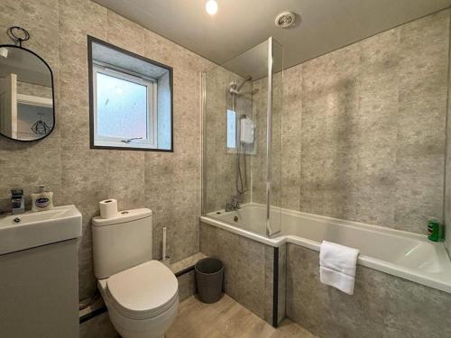 a bathroom with a toilet and a tub and a sink at Shrewsbury Townhouse in Harlescott