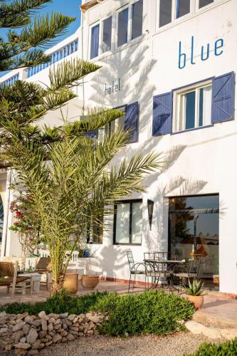 a white building with a blue sign on it at Blue Kaouki Boutique Hotel in Sidi Kaouki