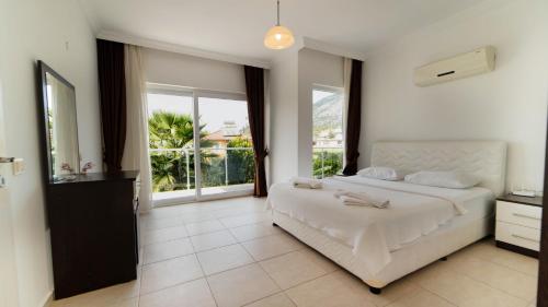 1 dormitorio con cama blanca y ventana grande en Villa Valley 6, 4 Bedroom, Private Arge Pool, Near Aquapark, en Fethiye