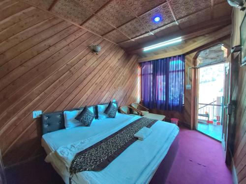 sypialnia z łóżkiem w pokoju z drewnianymi ścianami w obiekcie Goroomgo Lake View Mall Road Nainital - Mountain View & Spacious Room w mieście Nainital