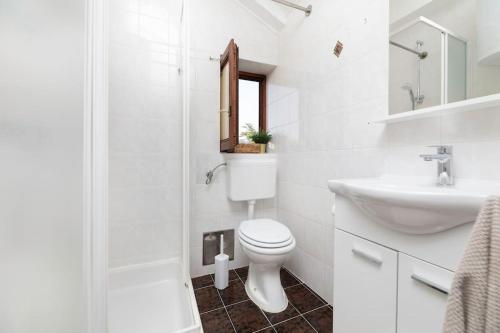 a white bathroom with a toilet and a sink at Apartment Olive - wonderful sea view in Punat