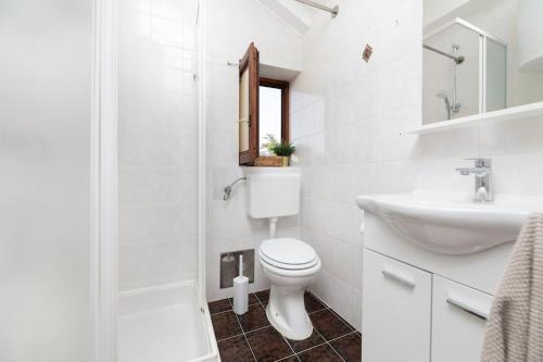 a white bathroom with a toilet and a sink at Apartment Olive with wonderful sea view - 500 m from beach in Punat