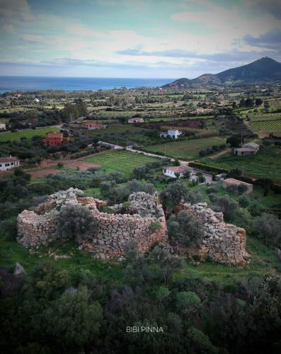 an old stone building in a field with the ocean at Villino Elisa in Tertenìa