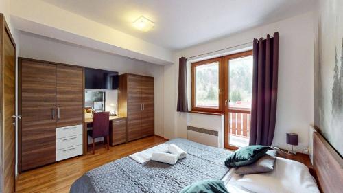 a bedroom with a bed and a window and a desk at Kamzik Apartment hill view with garage in Donovaly