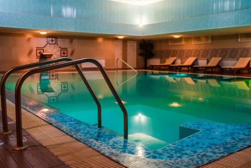 ein großer Pool mit Treppe in einem Hotel in der Unterkunft Хотел Казанлък in Kasanlak