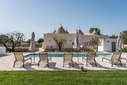 a group of lawn chairs and umbrellas next to a pool at Trullo Jalè - Boutique Apartments in Ostuni