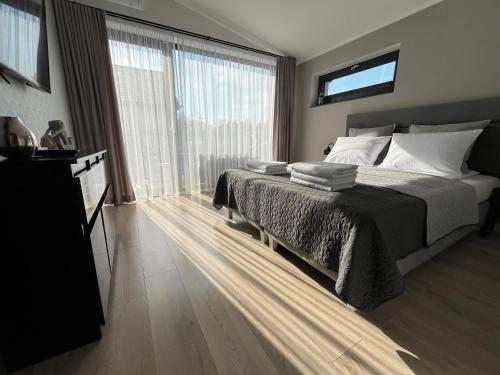 a bedroom with a bed and a large window at Apartamenty BLAST nad morzem Chłopy in Chłopy