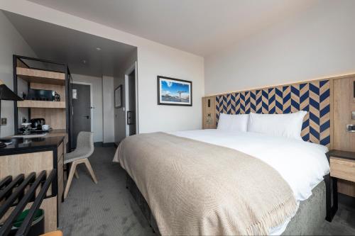 a hotel room with a large bed and a desk at Sandman Signature Glasgow Hotel in Glasgow