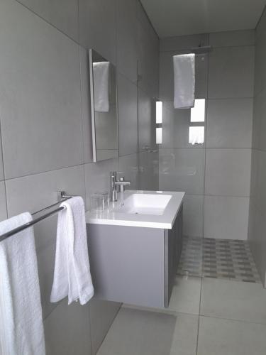 a white bathroom with a sink and a mirror at PULA NALA LODGE in Rustenburg