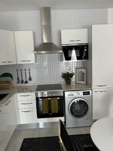 a kitchen with a washing machine and white cabinets at The Lennox by Luxe Properties in Accra