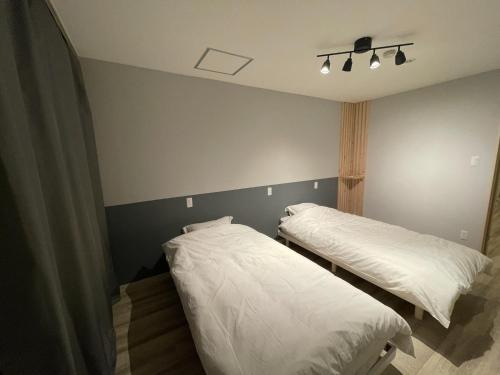 two beds in a room with white sheets at &HouSE - Vacation STAY 93911v in Takagi